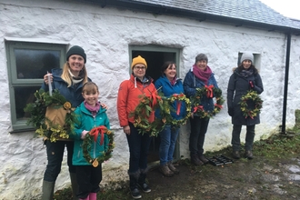 Six people stand in front of Bryn Golau cottage with Christmas wreaths