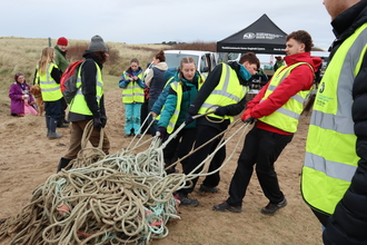 Volunteers dragging a large amount of fishing rope