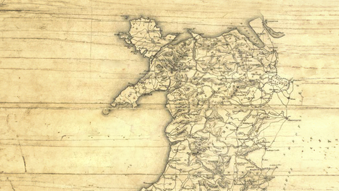 An old style map of Wales, with a sepia wood effect background and hand drawn look.